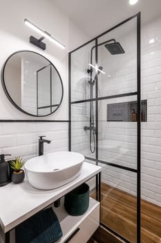 Simple bathroom with black shower, round mirror and classic white tiles.
