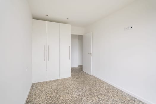 Interior of empty apartment, white room with wardrobe and tiled floor.