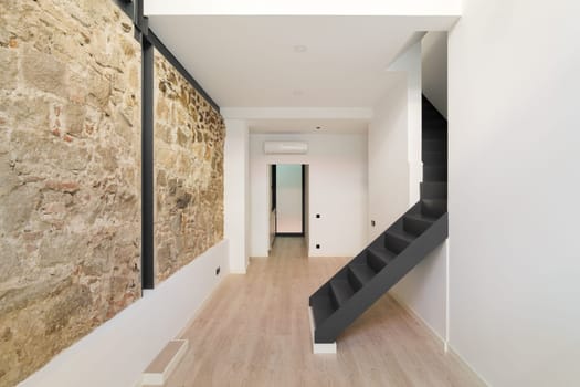 Mix of new and old architecture. Refurbished apartment with restored ancient wall left from old city buildings. Interior of empty renovated room in a duplex flat