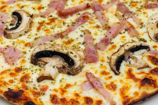 Close-up of pizza topped with mushrooms, ham, cheese and oregano. Selective focus.