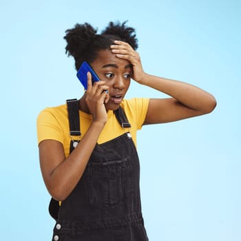 Shocked, surprised and black woman on a phone call for news isolated on a blue background in studio. Wow, crazy and African girl talking about gossip and bad communication on a mobile on a backdrop.