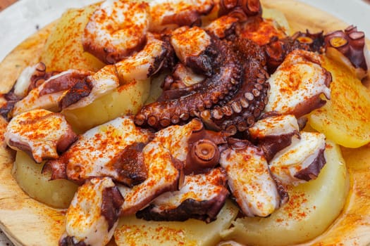 Fried octopus with potatoes and paprika on a plate in a restaurant.