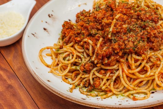 Spaghetti bolognese - pasta with minced meat and vegetables. Horizontal side view on wooden background.