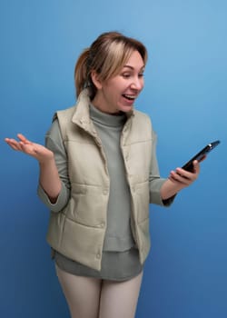 joyful blond millennial woman watching broadcast on smartphone.