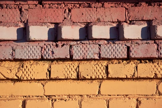 The background of a yellow and brown brick wall is the texture of a wall made of bright yellow and brown bricks, a wall painted in yellow and brown