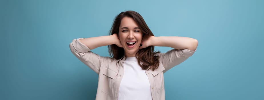 European model appearance young dark-haired lady in informal clothes posing against a blue background.