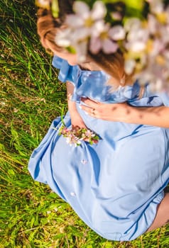 Pregnant woman in the garden of flowering apple trees. Selective focus. Nature.