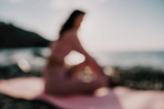 Young woman with black hair, fitness instructor in pink sports leggings and tops, doing pilates on yoga mat with magic pilates ring by the sea on the beach. Female fitness daily yoga concept