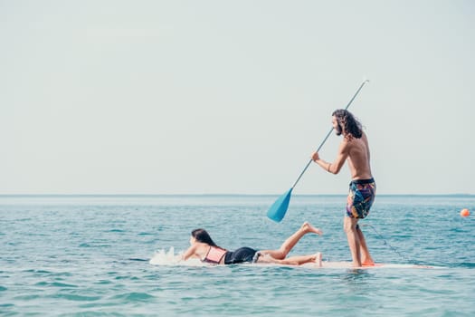 Silhouette of woman standing, surfing on SUP board, confident paddling through water surface. Idyllic sunset or sunrise. Sports active lifestyle at sea or river.