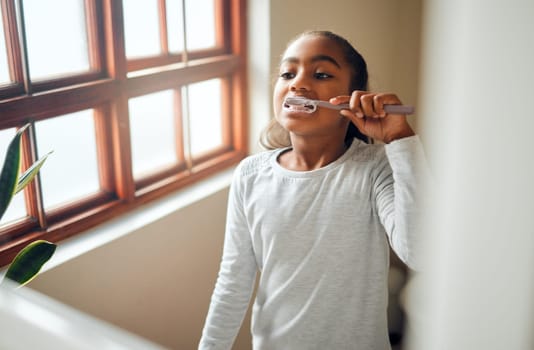 Girl brushing teeth, dental and toothbrush for hygiene with clean mouth and fresh breath with oral health. Kid, cleaning with toothpaste in bathroom and wellness at family home with healthy gums.