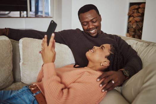 Black couple, phone and home wifi for internet connection while together on living room couch with love. Young man and woman talking while streaming online for communication or ecommerce subscription.
