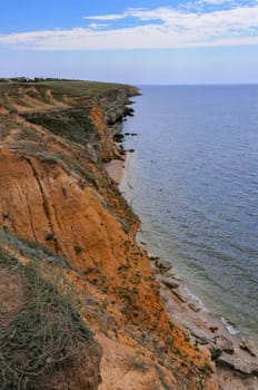 Steep rocky clay shore overgrown with steppe vegetation in eastern Crimea