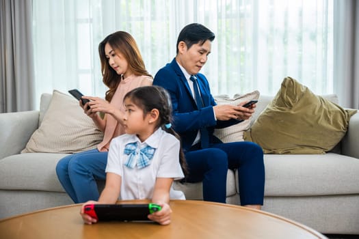 Family don't care about each other. Asian parents ignore their child and looking at their mobile phone at home, gadgets dependence overuse internet social media addiction on sofa living room