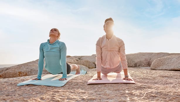 Pilates, stretching and woman friends on the beach together for mental health, wellness or balance in summer. Exercise, diversity or nature with a yoga female and friend outside for inner peace.