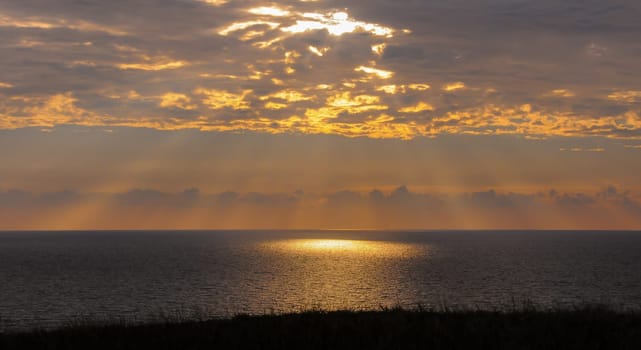 Colorful orange sunrise over the sea, sunbeams in the clouds