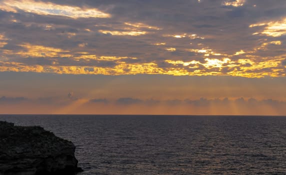 Colorful orange sunrise over the sea, sunbeams in the clouds