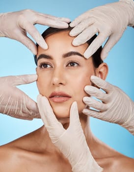 Plastic surgery, check and hands on the face of a woman isolated on a blue background in a studio. Feeling, skincare and doctors touching a model for a botox, cosmetics or dermatology consultation.