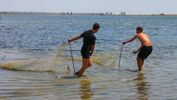 ODESSA, UKRAINE - JUNE 30, 2007: Fishermen catch fish with a net in a shallow pond, Tiligulsky Estuary Ukraine