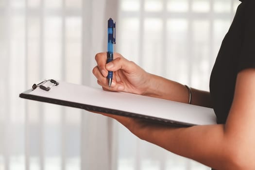 Hand holding a clipboard and taking note on the paper for the concept of work and study.