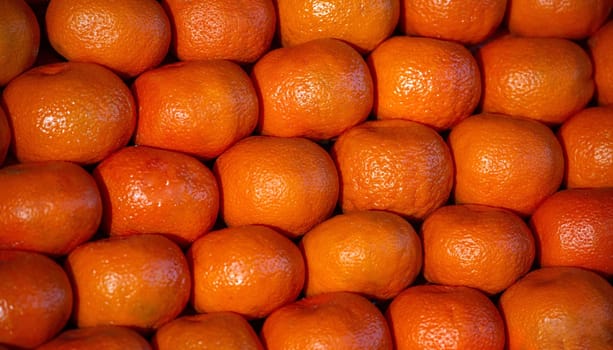 Tangerines as the background. Tangerines, mandarins fruits, bright orange color stacked on a market stall, full frame background, closeup view.