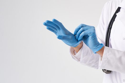 Close up of a female doctor putting latex gloves on a white background