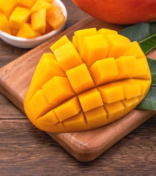 Fresh Mango - Juicy chopped mango cubes on wooden cutting board and rustic timber background. Tropical summer concept. Close up, macro, copy space. 