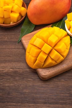 Fresh Mango - Juicy chopped mango cubes on wooden cutting board and rustic timber background. Tropical summer concept. Close up, macro, copy space. 