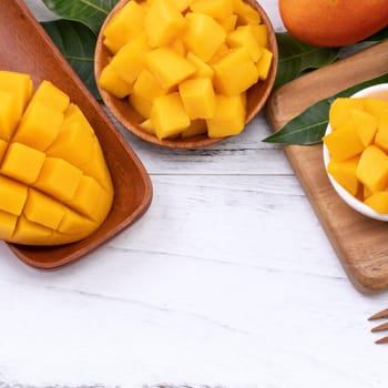 Fresh chopped mango on a tray and bright rustic wooden background. Tropical summer fruit design concept, close up, macro, copy space.