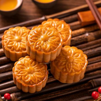 Moon cake Mooncake table setting - Round shaped Chinese traditional pastry with tea cups on wooden background, Mid-Autumn Festival concept, close up.