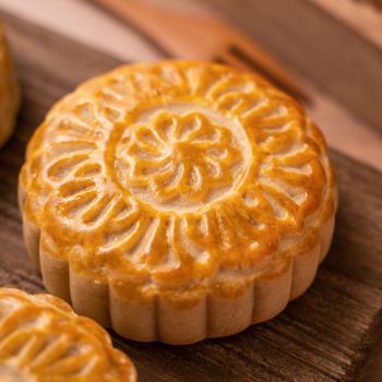 Round shaped moon cake Mooncake - Chinese style traditional pastry during Mid-Autumn Festival / Moon Festival on wooden background and tray, close up