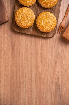 Round shaped moon cake Mooncake - Chinese style pastry during Mid-Autumn Festival / Moon Festival on wooden background and tray, top view, flat lay.