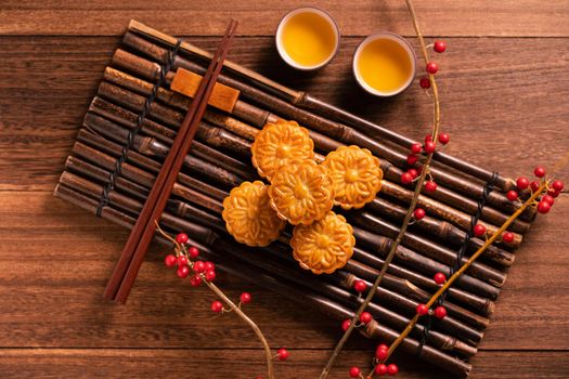 Moon cake Mooncake table setting - Chinese traditional pastry with tea cups on wooden background, Mid-Autumn Festival concept, top view, flat lay.