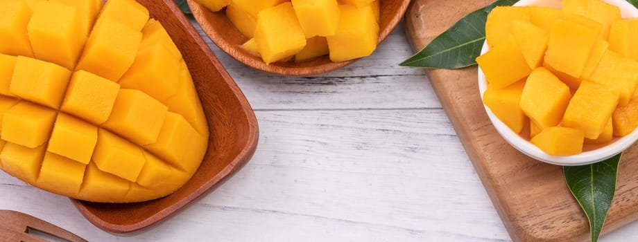 Fresh chopped mango on a tray and bright rustic wooden background. Tropical summer fruit design concept, close up, macro, copy space.