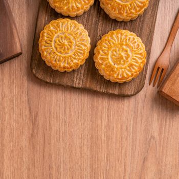 Round shaped moon cake Mooncake - Chinese style pastry during Mid-Autumn Festival / Moon Festival on wooden background and tray, top view, flat lay.