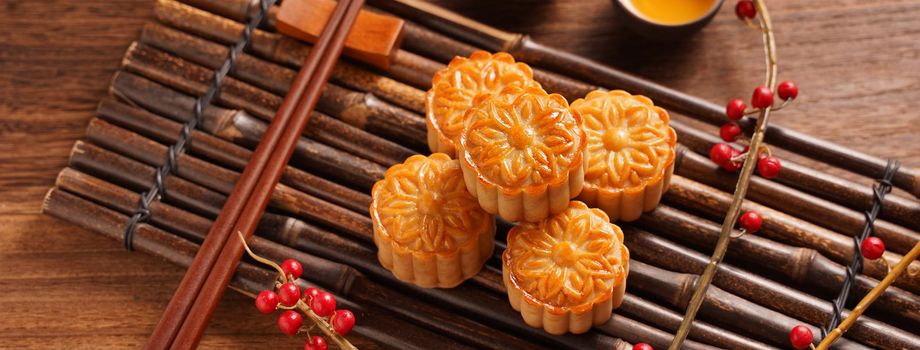 Moon cake Mooncake table setting - Round shaped Chinese traditional pastry with tea cups on wooden background, Mid-Autumn Festival concept, close up.