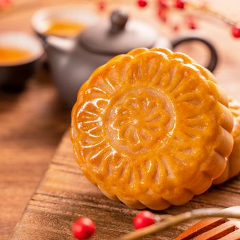 Moon cake Mooncake table setting - Round shaped Chinese traditional pastry with tea cups on wooden background, Mid-Autumn Festival concept, close up.