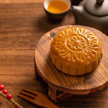 Moon cake Mooncake table setting - Round shaped Chinese traditional pastry with tea cups on wooden background, Mid-Autumn Festival concept, close up.