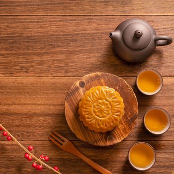 Moon cake Mooncake table setting - Chinese traditional pastry with tea cups on wooden background, Mid-Autumn Festival concept, top view, flat lay.