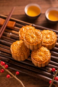 Chinese traditional pastry Moon cake Mooncake with tea cups on bamboo servingwarning tray on wooden background for Mid-Autumn Festival, close up.