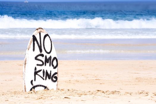 No Smoking warning sign on white surfboard at the beach in summer, concept of sea environmantal protection design, copy space, lifestyle.