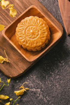 Mid-Autumn Festival traditional food concept - Beautiful Moon cake on black slate table with tea, pastry mold, flower, top view, flat lay, copy space