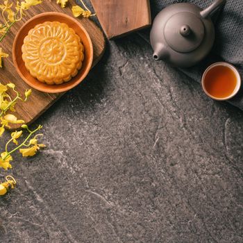 Mid-Autumn Festival traditional food concept - Beautiful Moon cake on black slate table with tea, pastry mold, flower, top view, flat lay, copy space