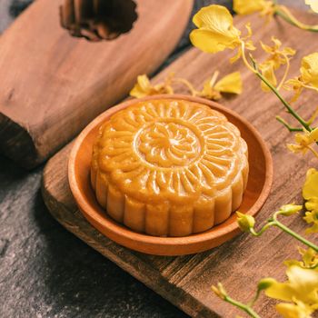 Mid-Autumn Festival traditional food concept - Beautiful Moon cake on black slate table with tea, pastry mold, flower, close up, copy space