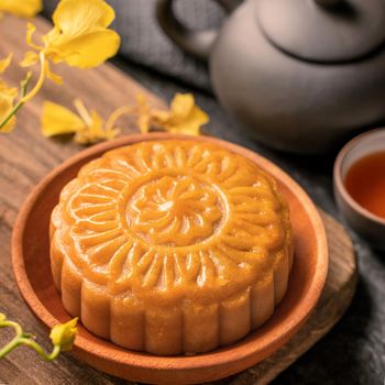 Mid-Autumn Festival traditional food concept - Beautiful Moon cake on black slate table with tea, pastry mold, flower, close up, copy space