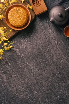 Mid-Autumn Festival traditional food concept - Beautiful Moon cake on black slate table with tea, pastry mold, flower, top view, flat lay, copy space