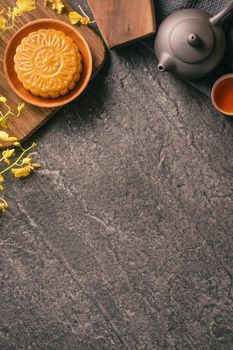 Mid-Autumn Festival traditional food concept - Beautiful Moon cake on black slate table with tea, pastry mold, flower, top view, flat lay, copy space