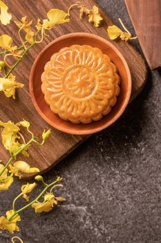 Mid-Autumn Festival traditional food concept - Beautiful Moon cake on black slate table with tea, pastry mold, flower, top view, flat lay, copy space