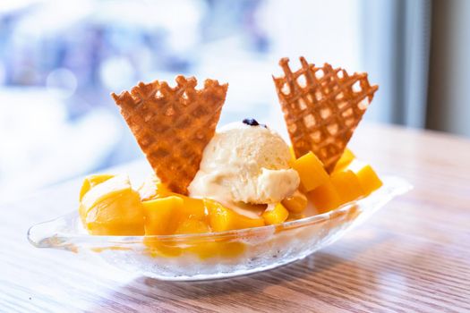 Fresh mango shaved ice with a scoop of ice cream and juice sauce in summer restaurant, lifestyle, popular food in Taiwan, close up.