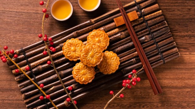 Chinese traditional pastry Moon cake Mooncake with tea cups on bamboo serving tray on wooden background for Mid-Autumn Festival, top view, flat lay.