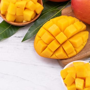 Fresh chopped mango on a tray and bright rustic wooden background. Tropical summer fruit design concept, close up, macro, copy space.